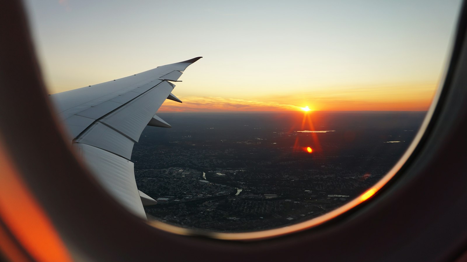 Aircraft wing at sunset seen through a cabin window